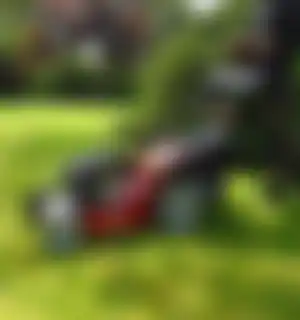 foto van iemand die met een grasmaaier door de tuin loopt